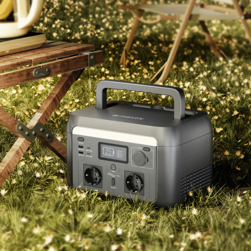 Mestic Power Station im Outdoor Camping Einsatz auf Wiese neben Campingtisch mit Tragegriff und Steckdosen