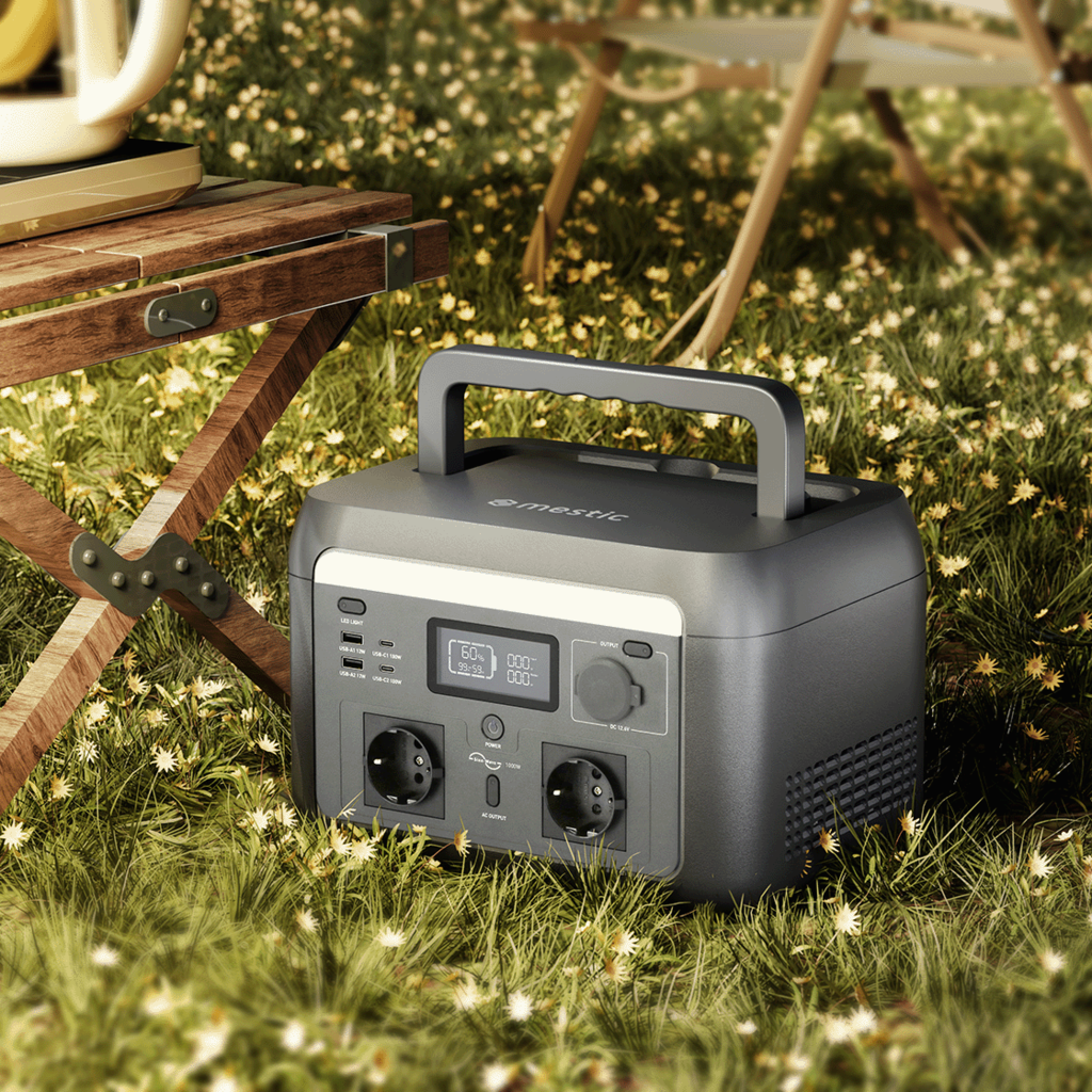 Mestic Power Station im Outdoor Camping Einsatz auf Wiese neben Campingtisch mit Tragegriff und Steckdosen